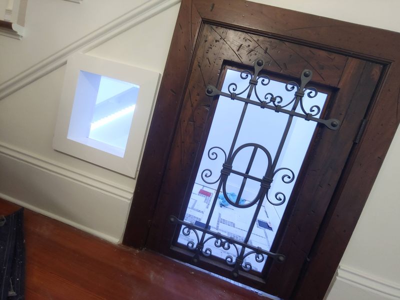 Wrought iron and stained wood door set under a staircase