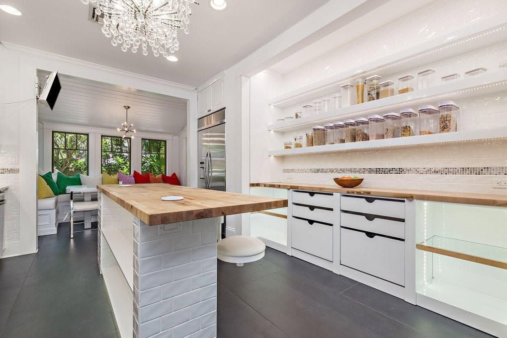Kitchen pantry with lit floating shelves, mosaic tile band, and drawers